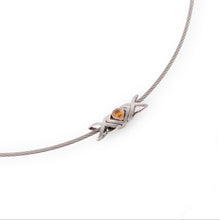 Load image into Gallery viewer, Stainless steel XOX plaque on a stainless steel wire necklace: two X's with one O in the middle set with 2 4mm orange Spessatine garnet stones. The jewelry is set on a white background. Outwitting injustice with love for humanity.